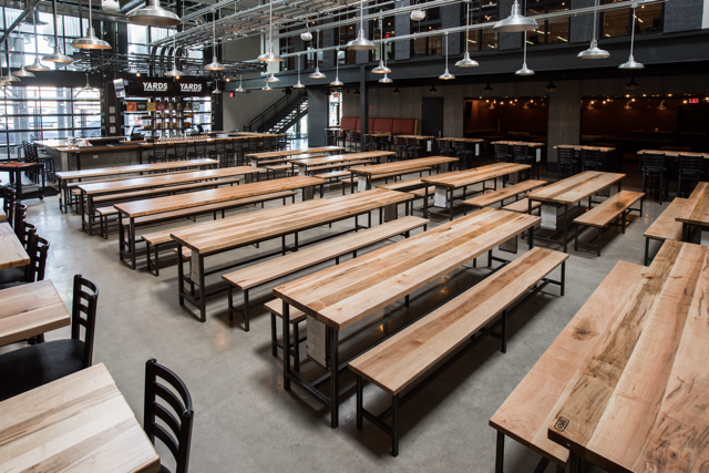 Dining hall with several long light wood tables and matching benches